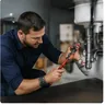 A plumber working on pipework under a sink